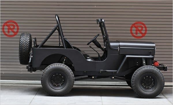 Zwarte, eenvoudige Willys MB-jeep in zijaanzicht met terreinbanden